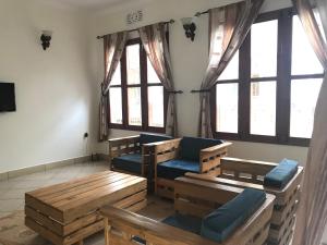 una sala de estar con bancos y ventanas de madera. en Le Parlour, en Boma la Ngombe