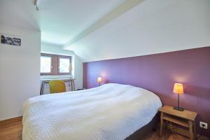 ein Schlafzimmer mit einem weißen Bett und einer lila Wand in der Unterkunft Gite des Coteaux in Lüttich