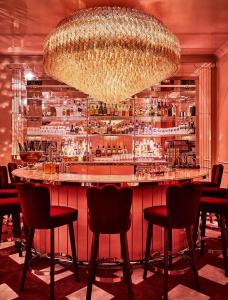 um bar com cadeiras vermelhas e um grande lustre em The Siren Hotel em Detroit