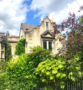 uma velha casa de pedra com árvores em frente em Lauras Townhouse Apartments Dressmakers Salon em Bath