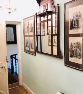 a hallway with pictures and a clock on a wall at Lauras Townhouse Apartments Dressmakers Salon in Bath