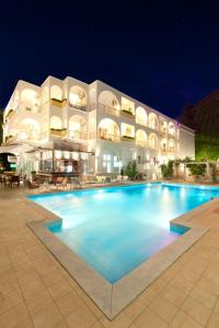 a large pool in front of a building at night at Kronos Hotel in Platamonas