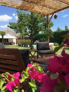 a patio with two chairs and pink flowers at Les Tignoliers in Tignieu-Jameyzieu