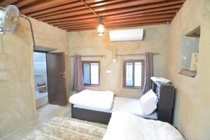 um quarto com duas camas e uma televisão em Basmat almisfah em Al Ḩamrāʼ