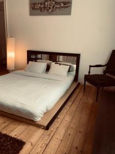 uma cama com lençóis brancos e uma cadeira num quarto em Chic Cocoon Guest House em Bruxelas