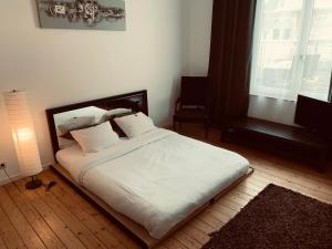 - une chambre avec un lit doté de draps et d'oreillers blancs dans l'établissement Chic Cocoon Guest House, à Bruxelles