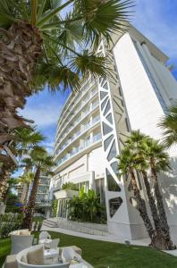 a building with palm trees in front of it at Hotel Sporting in Rimini