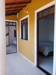 Habitación con cama y puerta con dormitorio en Lugar Paradisiaco 200 m praia en Camaçari