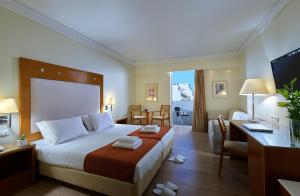 a hotel room with a large bed and a desk at Atrion Hotel in Heraklio