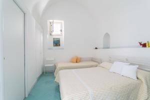 アマルフィにあるCasa Novellaの白い壁と青い床の客室で、ベッド2台が備わります。