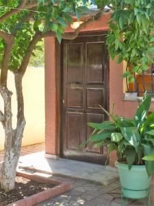 a large wooden door of a house with a tree at Cosy guesthouse-souterrain with garden in city center in Korinthos