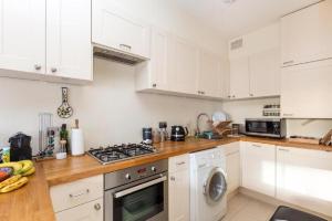 a kitchen with white cabinets and a stove top oven at 1-bed flat at the heart of Fulham & Parsons Green! in London