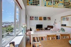 Beautiful duplex penthouse - roof garden, views, parking في نيوكاسل أبون تاين: غرفة معيشة مع نافذة كبيرة وأريكة
