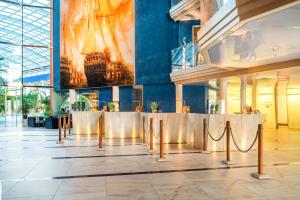 a lobby with tables and a large painting on the wall at Hotel Victory Therme Erding in Erding