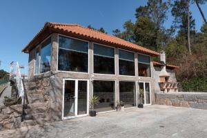 ein Haus mit großen Fenstern und einem Dach in der Unterkunft O Sequeiro in Vila Nova de Famalicão