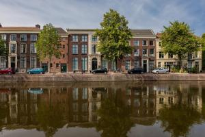 ein Gebäude mit Autos, die neben einem Wasserkörper geparkt sind in der Unterkunft Stadsvilla Mout Rotterdam-Schiedam in Schiedam