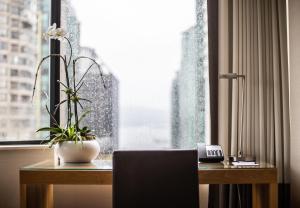 a room with a desk with a plant and a window at The Listel Hotel Vancouver in Vancouver