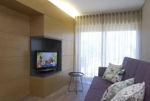 uma sala de estar com um sofá e uma televisão na parede em Gare da Fonte Nova - Aveiro em Aveiro