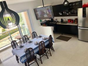 a kitchen with a table and chairs and a refrigerator at Apartamento Familiar Guaruja in Guarujá