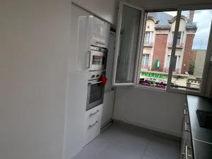 cocina con nevera blanca y ventana en Appartement 3 pièces, en Noisy-le-Sec