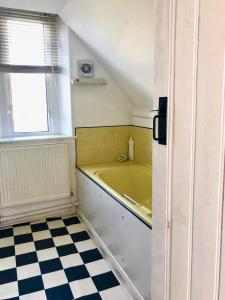 a bathroom with a tub and a checkered floor at Lauras Townhouse Apartments Skylight Loft in Bath