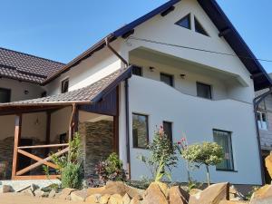 a white house with a stone wall at Casa de vacanta Sabrina in Gura Humorului