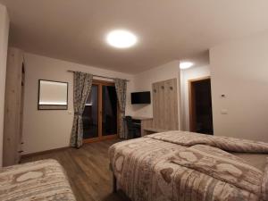 a hotel room with two beds and a desk at All'Amicizia in Santo Stefano di Cadore
