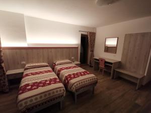sypialnia z 2 łóżkami, biurkiem i lustrem w obiekcie All'Amicizia w mieście Santo Stefano di Cadore
