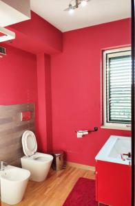ein rotes Badezimmer mit WC und Waschbecken in der Unterkunft Villetta tra gli agrumeti in Corigliano Calabro