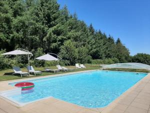 a swimming pool with chairs and umbrellas in a yard at Domaine LES OURGEAUX in Pagéas