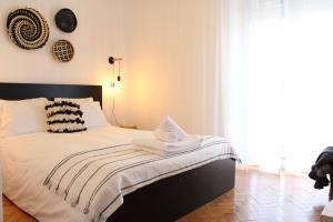 um quarto com uma cama com lençóis brancos e uma janela em Bela Casa - Modern Designer Chic Central Coimbra em Coimbra