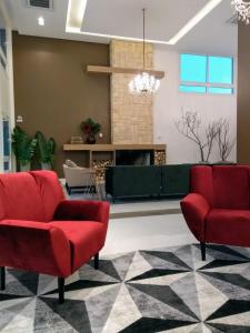 een woonkamer met 2 rode stoelen en een open haard bij Hotel Alles Berg in Nova Petrópolis
