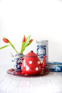 a red tea pot sitting on a table with a vase at Jackie O Studio in Amsterdam