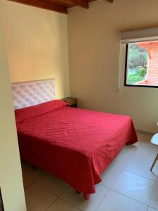 a bedroom with a red bed with a window at Departamentos Le Forêt in Mar de Ajó +18 photos