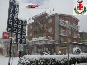 un hélicoptère rouge survolant un bâtiment dans la neige dans l'établissement Albergo Motel Dosdè, à Grosio