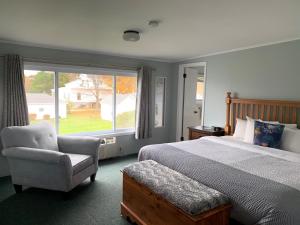 a bedroom with a bed and a chair and a window at Beachfront Inn in Baileys Harbor