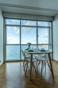 comedor con mesa y sillas y ventana grande en APARTAMENTO CON INCREIBLES VISTAS A LA PLAYA DE RIAZOR en A Coruña