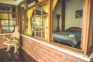 Dormitorio con ventana y cama. en Hostal Las Palmas, en Puyo