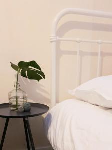 een slaapkamer met een wit bed en een tafel met een plant bij Appartement Plek in Holten in Holten