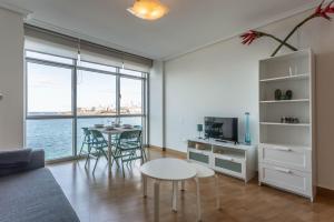 een woonkamer met een tafel en een keuken met uitzicht bij Apartamentos Alocea in A Coruña