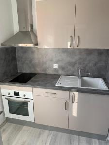 een witte keuken met een wastafel en een fornuis bij Charmant studio avec climatisation et parking in Perpignan