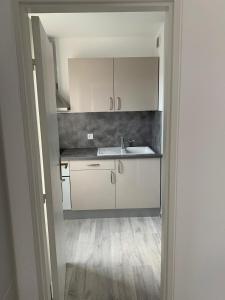 a kitchen with white cabinets and a sink at Charmant studio avec climatisation et parking in Perpignan