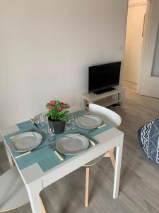 a dining room table with plates and flowers on it at Charmant studio avec climatisation et parking in Perpignan