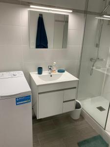 een witte badkamer met een wastafel en een douche bij Charmant studio avec climatisation et parking in Perpignan