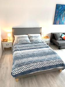 een bed in een slaapkamer met 2 nachtkastjes en 2 tafels bij Charmant studio avec climatisation et parking in Perpignan