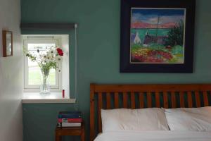 Un dormitorio con una cama y un jarrón de flores en una ventana en Macleod Cottage - Isle of Lewis Self-Catering en Port of Ness