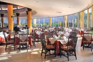 un comedor con mesas, sillas y ventanas en Barceló Maya Tropical - All Inclusive en Xpu Ha