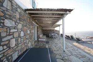 a patio with a stone wall and a table and chairs at Blue Ocean Mykonos in Ornos