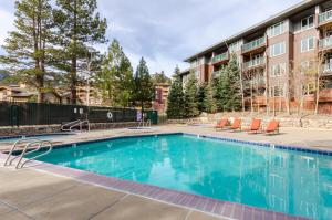 a swimming pool with chairs and a building at Juniper Springs Lodge #238 in Mammoth Lakes