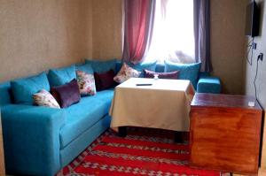 a blue couch with a table in a living room at Residence Touristique Merzouga in Merzouga